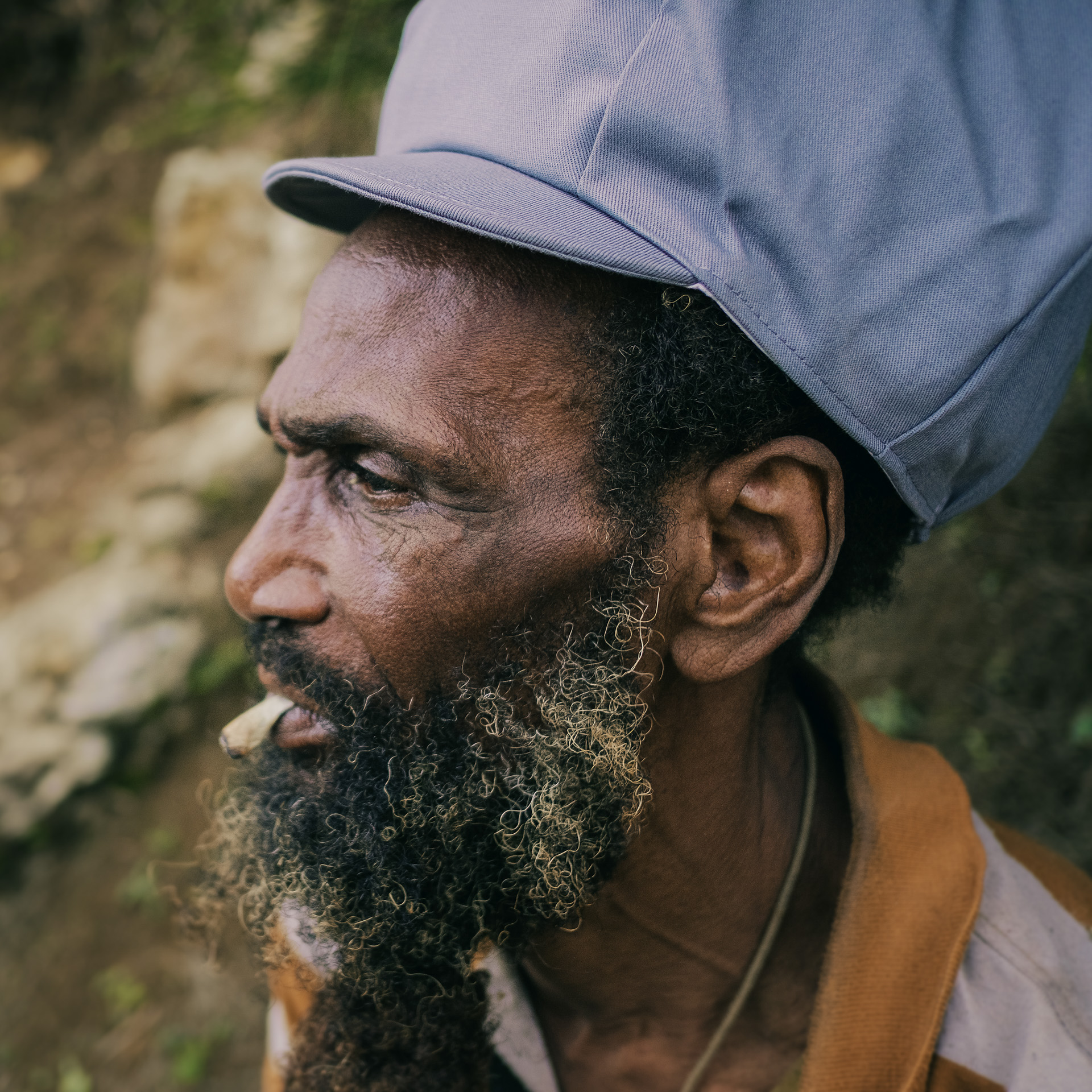 Jamaican Rasta Clifford wearing grey dreadlocks cap and smoking a spliff